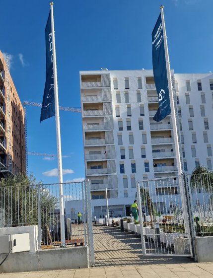 Mástil en fibra de vidrio con potencia y banderas. Dado de hormigón. Para Deacapital en Entrenúcleos Dos Hermanas Sevilla.